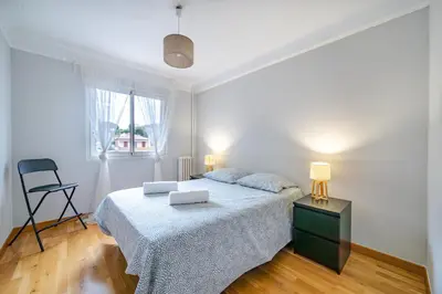 a white bedroom with a bed and a chair at Appartement en plein coeur de Cagnes sur Mer in Cagnes-sur-Mer