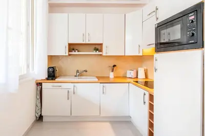 a white kitchen with a sink and a microwave at 50 meters from the beach ! Best location in Nice in Nice