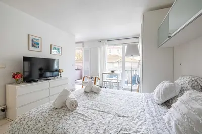 a white bedroom with a bed and a television at Charming Studio with pool & balcony -Heart of Nice in Nice