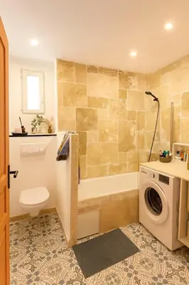 a bathroom with a tub and a toilet and a washing machine at Le Grand Ruisseau in Nice