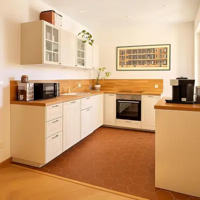 a kitchen with white cabinets and a brown floor at Le Grand Ruisseau in Nice