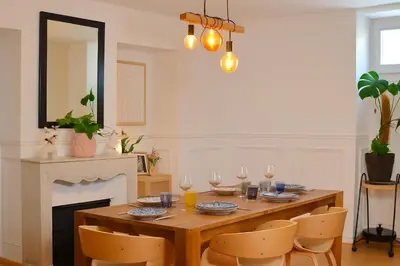 a dining room with a table with chairs and a mirror at Le Grand Ruisseau in Nice