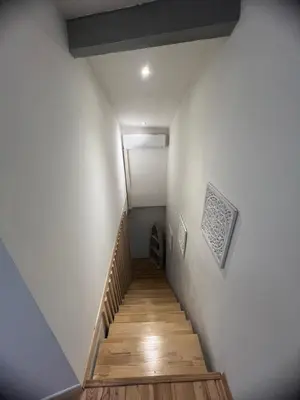 a staircase in a room with white walls and wooden floors at Duplex quatre pièces - une chambre bébé à 5 minutes de la plage in Nice