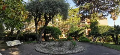 a park with a bench and trees and a building at 2 pièces au calme avec terrasse et climatisation in Nice