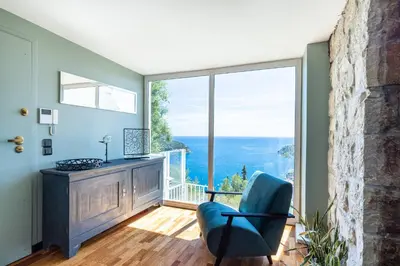 a living room with a chair and a large window at 73 CORNE D OR - Toit Terrasse - Vue Mer Panoramique - Jaccuzzi in Villefranche-sur-Mer