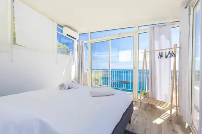 a bedroom with a large window with a view of the ocean at 73 CORNE D OR - Toit Terrasse - Vue Mer Panoramique - Jaccuzzi in Villefranche-sur-Mer