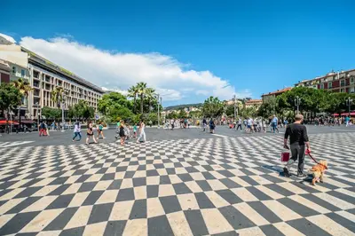 a man walking a dog on a checkered street at RIVIERA COZY - Place Massena in Nice