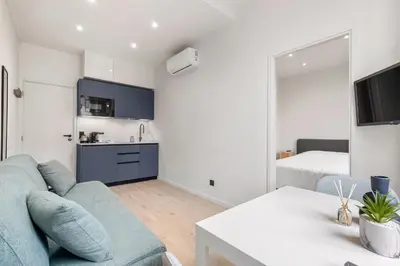 a living room with a blue couch and a kitchen at RIVIERA COZY - Place Massena in Nice