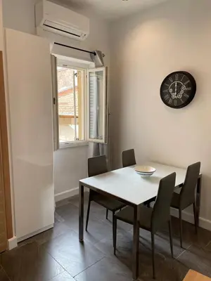 a dining room with a table and chairs and a clock at Massena : Hyper Centre Studio 2p in Nice