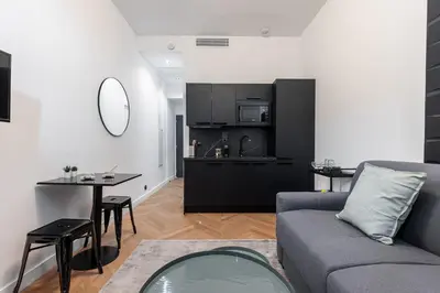a living room with a couch and a table and a kitchen at 7 FOCH 202 - Studio contemporain en plein coeur de Nice - climatisation in Nice