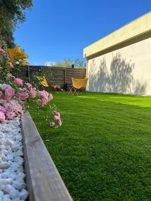 a backyard with a lawn with flowers and a bench at Petite maison, cosy, sur les collines niçoises in Nice
