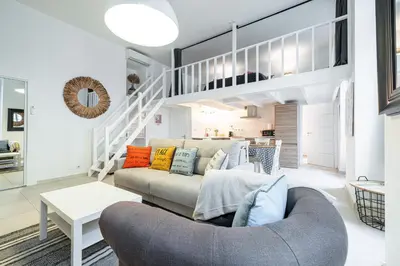 a living room with a couch and a staircase at La Petite Chaise Bleue Appartement classe 3 etoiles in Nice