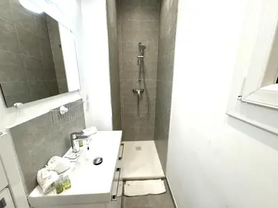 a white bathroom with a sink and a shower at ApartHotel Riviera - MAISON DU GRAND SUD - Confortable petit 3 pièces - Promenade des Anglais in Nice