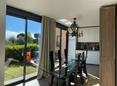 a dining room with a glass table and a kitchen at Rez de jardin avec vue mer à saint jean in Saint-Jean-Cap-Ferrat
