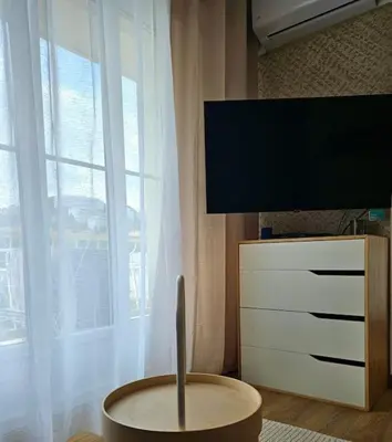 a living room with a tv and a table and a window at Le plein ciel Studio in Nice