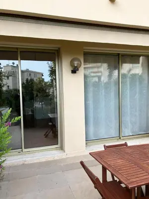 a patio with a wooden table and glass windows at Beaulieu in Beaulieu-sur-Mer