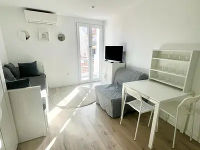 a living room with a table and a couch at Studio Moderne Rénové avec balcon in Nice