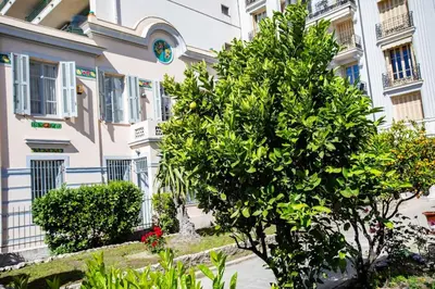 a tree in front of a building with a clock at #15 Sea front Villa AC stunning view for 6 pers wifi in Nice
