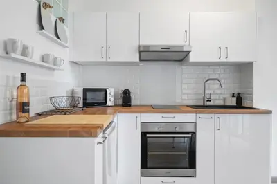 a white kitchen with white cabinets and a sink at Le Mistral in Nice