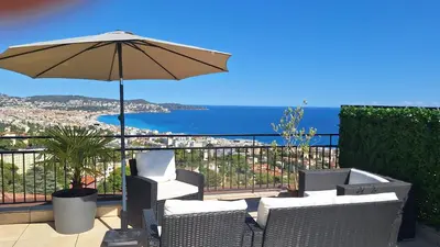 a patio with an umbrella and chairs and the ocean at Chambre d'hôtes pleine vue mer in Nice