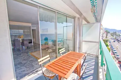 a balcony with a wooden table and chairs on a building at Luxury Sea Front Condo Milord in Nice