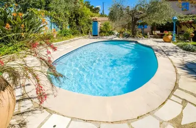 a swimming pool with blue water in a yard at Studio charmant à Cagnes-sur-Mer de 35 m² + piscine privée in Cagnes-sur-Mer