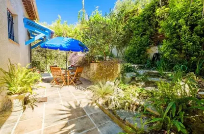 a patio with an umbrella and a pond at Studio charmant à Cagnes-sur-Mer de 35 m² + piscine privée in Cagnes-sur-Mer