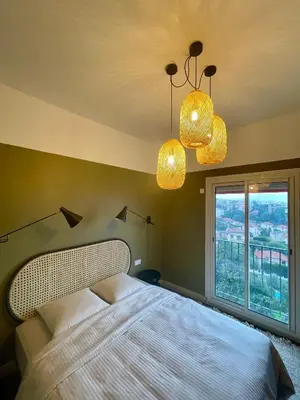 a bedroom with a bed and two lights and a window at Appartement moderne avec une belle vue in Nice