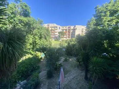 a garden with trees and a building in the background at Nice ouest-Cosy Studio, Clim Wifi in Nice