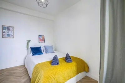 a bedroom with a bed with a yellow blanket and blue shoes on it at Maison Bianchi - Downtown Alsace Lorraine in Nice