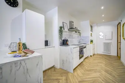 a kitchen with white counters and a wooden floor at Maison Bianchi - Downtown Alsace Lorraine in Nice