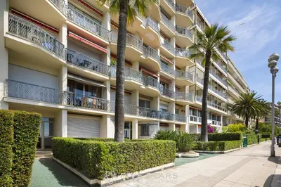 an apartment building with palm trees and a sidewalk at Suite Grand Sud FSHH in Nice