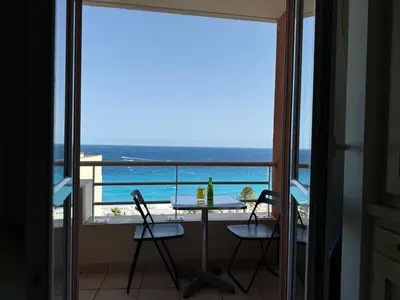 a view of a beach with palm trees and the ocean at VUE mer 02 chambres 45M et parking in Nice