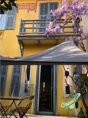 a yellow building with a table and chairs and an umbrella at Villa Nice in Nice
