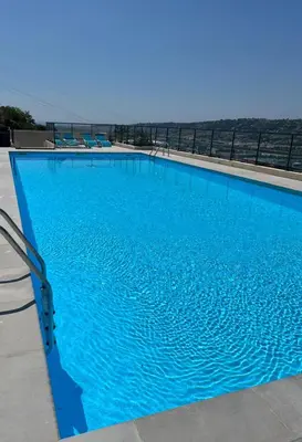 a large blue swimming pool with the ocean in the background at Joli 3 pièces ensoleillé sur les hauteurs de Nice in Nice