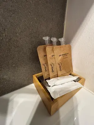a wooden tray with three bottles and towels at Nice appartement for 2 adults with air-conditioning in Nice