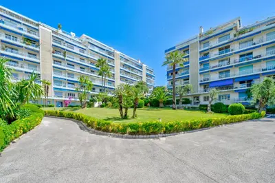 a large apartment building with palm trees and a park at Port de Nice, Charmant studio in Nice