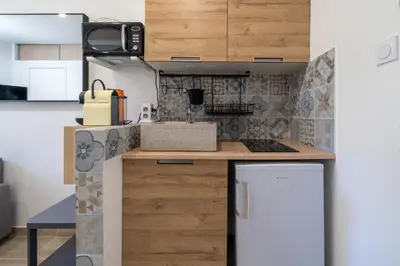 a kitchen with wooden cabinets and a white refrigerator at Port de Nice, Charmant studio in Nice