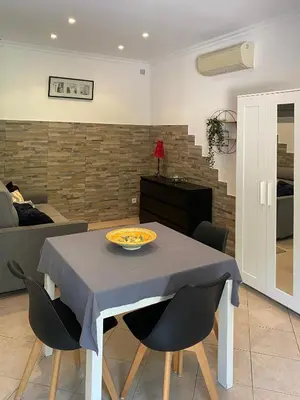 a dining room with a table and chairs and a living room at Villa Serenice - F2 au calme, climatisé, WIFI et parking gratuit in Nice