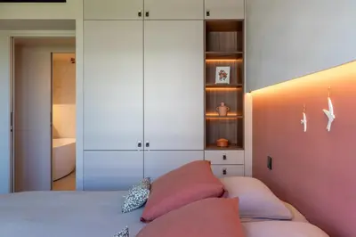 a bedroom with white cabinets and pink pillows on a bed at Les Belles Terres - Résidence avec piscine vue mer in Nice