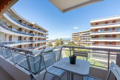 a balcony with a table and chairs and a building at Les Belles Terres - Résidence avec piscine vue mer in Nice