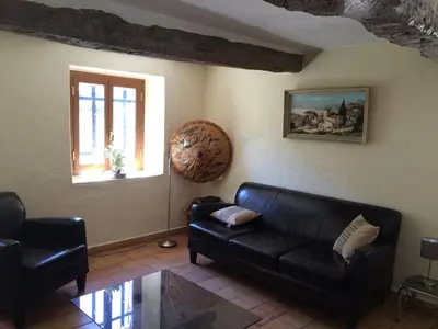 a living room with a black leather couch and a window at Maison de caractère in Saint-Jeannet