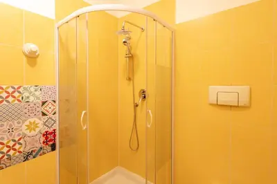 a shower stall in a bathroom with yellow tiles at #13 Orange suite AC Wifi Balcony 3mins walk sea front in Nice