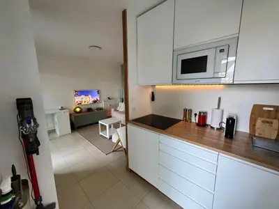 a kitchen with white cabinets and a living room at Art Studio Nice in Nice