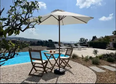 a table and two chairs under an umbrella next to a pool at DOMAINE LOU BEL AZUR - Elégant in Saint-Laurent-du-Var