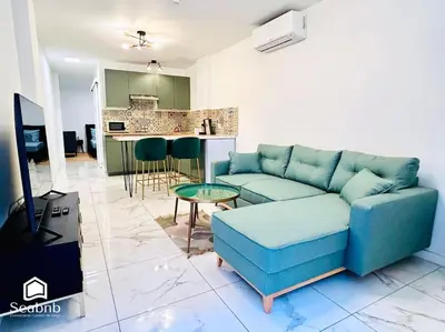 a living room with a blue couch and a kitchen at Charming Downtown - AC - WiFi - Private Entrance in Nice