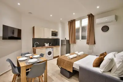 a bedroom with a bed and a table and a kitchen at Cosy Apparts Hypercentre de Nice in Nice