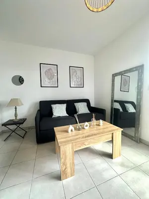 a living room with a couch and a wooden coffee table at Cosy studio avec parking et vue féerique in Nice