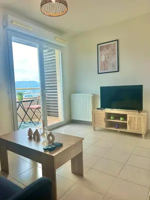 a living room with a flat screen tv and a table at Cosy studio avec parking et vue féerique in Nice