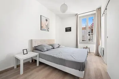 a white bedroom with a bed and a table at Magnifique 3 pièces de 80m2 dans le Carré d'Or in Nice